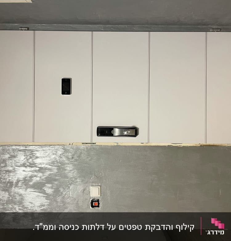 דלת לבנה עם ידית כסופה על קיר אפור